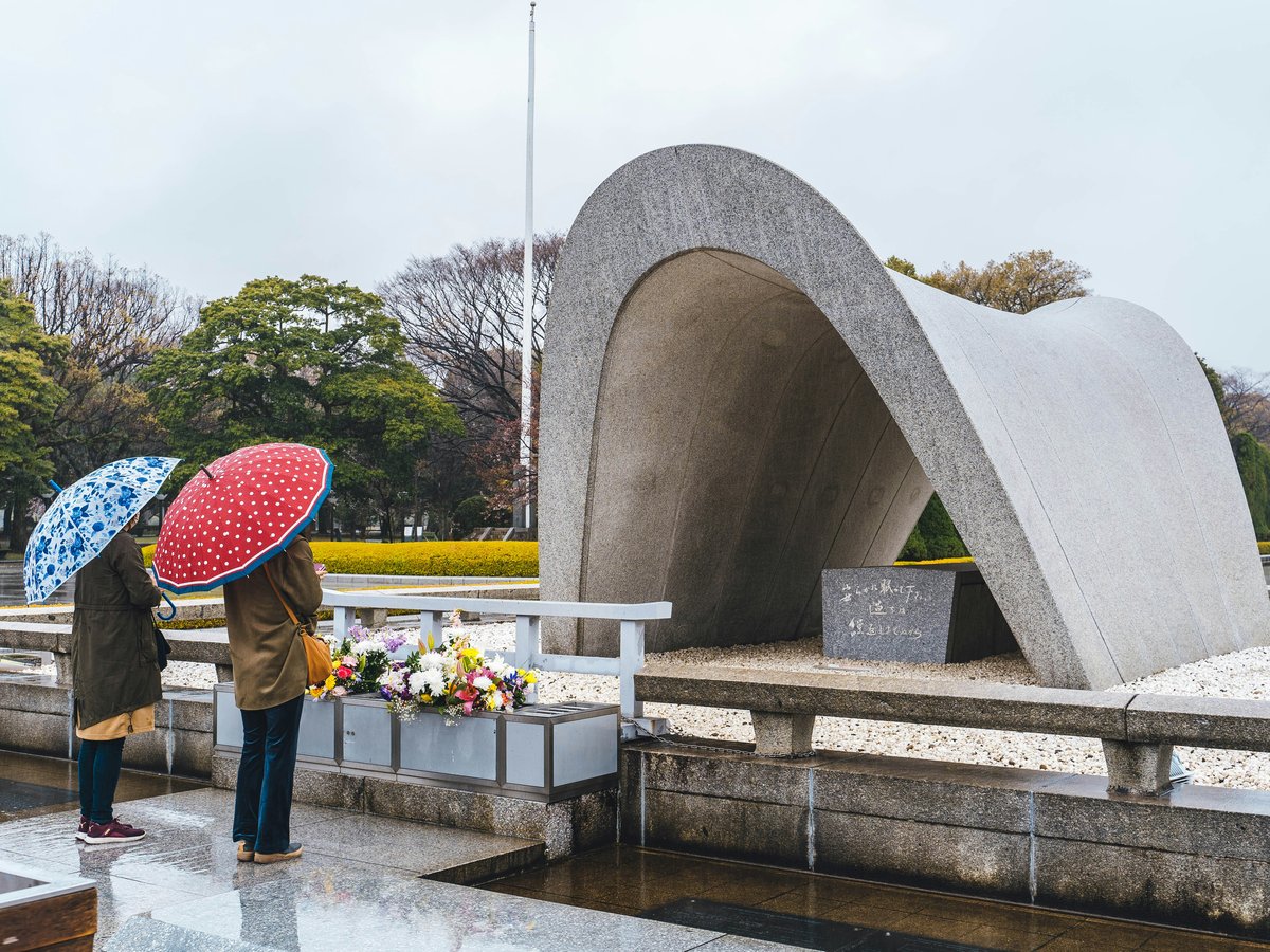 a couple of people stand near each other holding umbrellas
