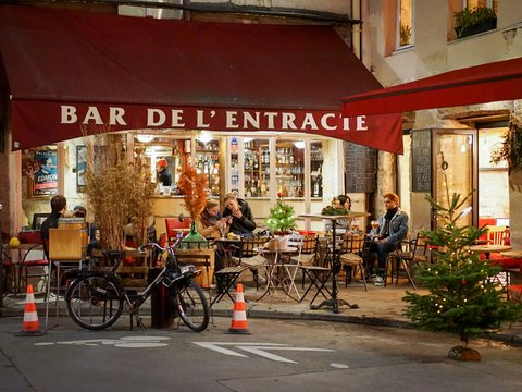 a group of people sitting at tables outside of a restaurant