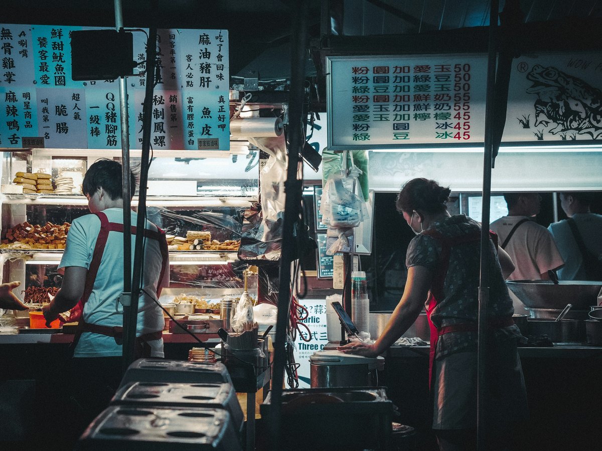 A group of people standing around a food stand