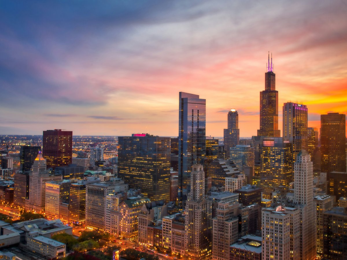 a view of a city at sunset from the top of a skyscraper