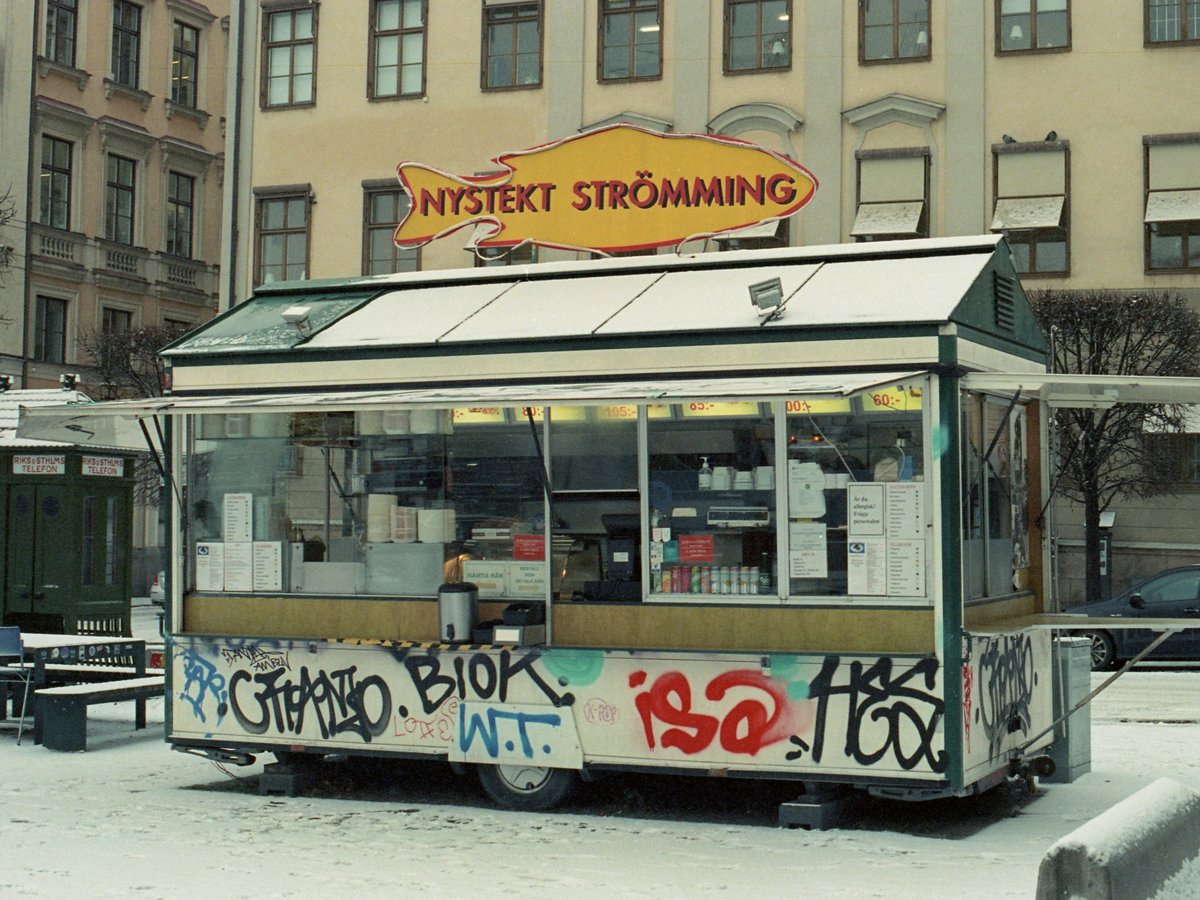 A street food cart covered in graffiti in front of a building