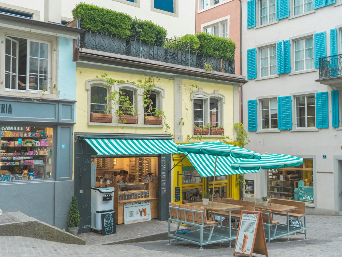 a street corner with tables and umbrellas in front of buildings