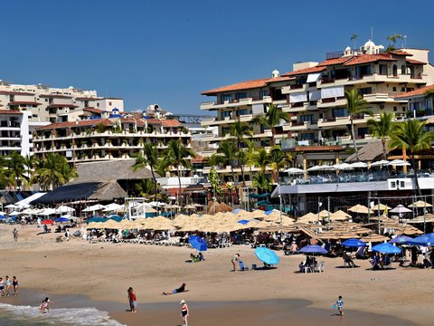 Beach with many umbrellas and buildings in the background