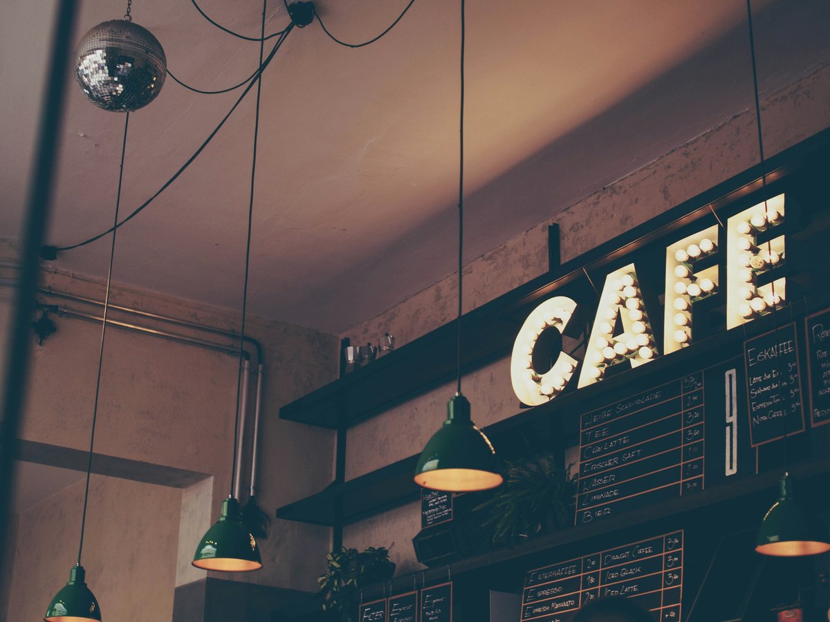 photography of cafe with LED signage and pendant lamps and menu boards