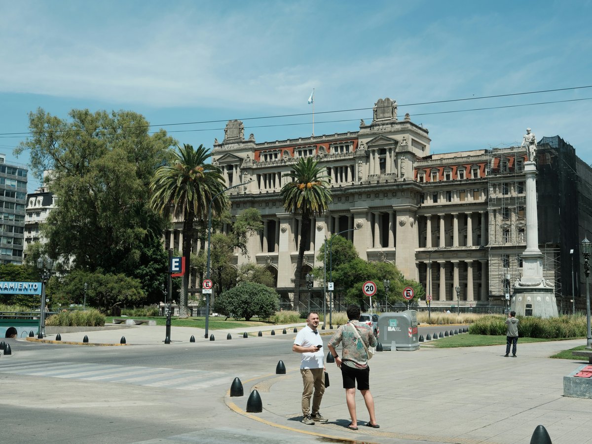 People in front of a grand historic building with trees.