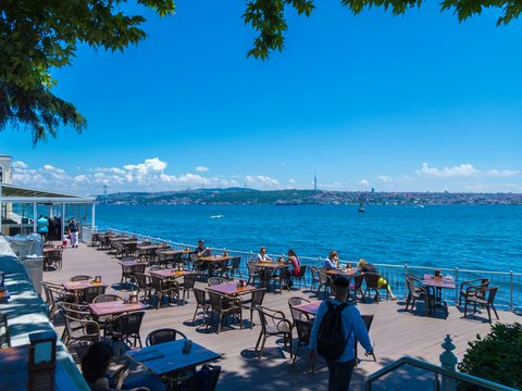 a group of people sitting at tables near the water