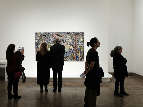 a group of people standing in front of a painting