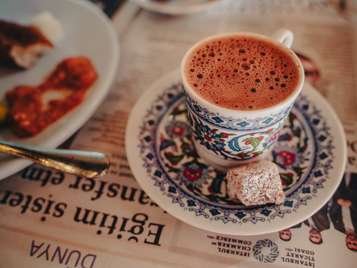 A cup of turkish coffee with a delight cube of turkish delight.