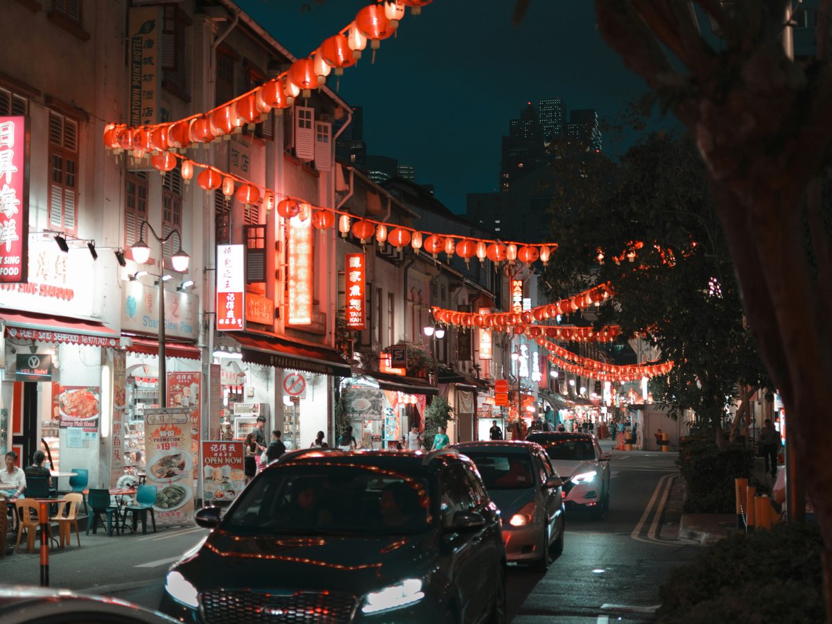 a street with cars and buildings with lights
