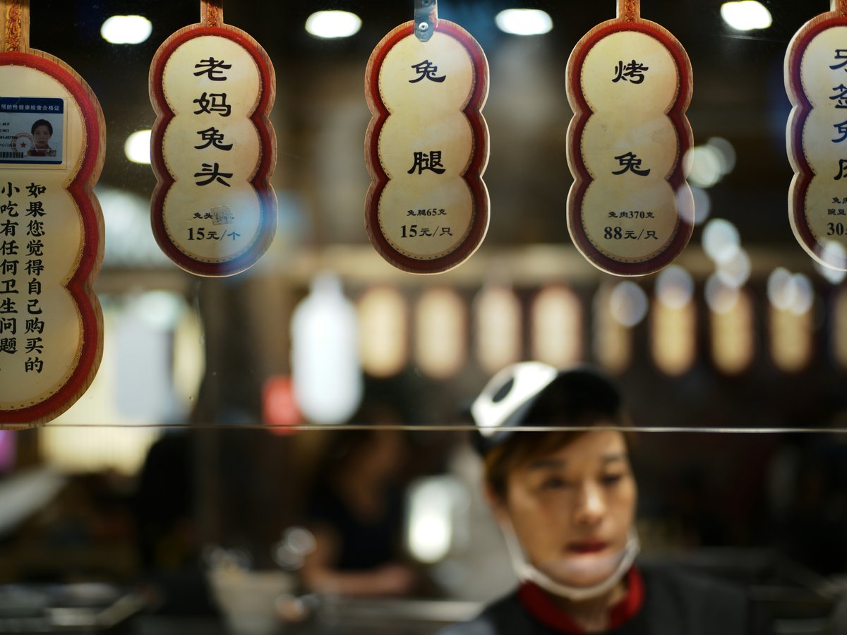 Asian food stall with hanging signs and blurred worker