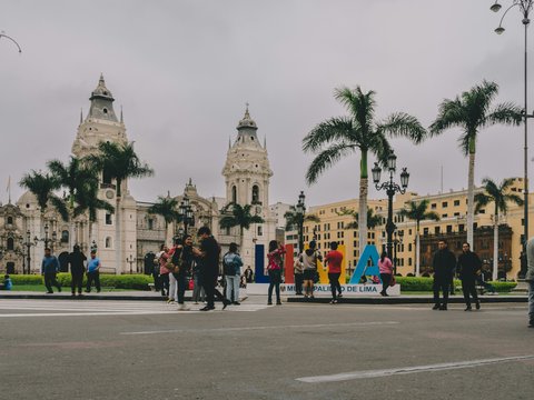 a group of people walking across a street next to tall buildings