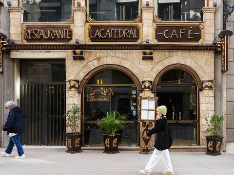 a man walking down a street past a cafe