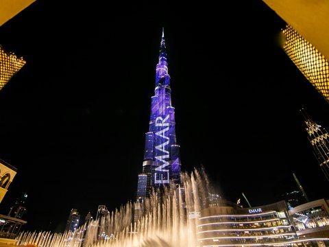 low angle view of fountain surrounded by buildings at night