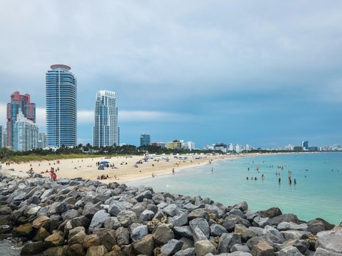 A view of a beach with people in the water and skyscrapers in the background