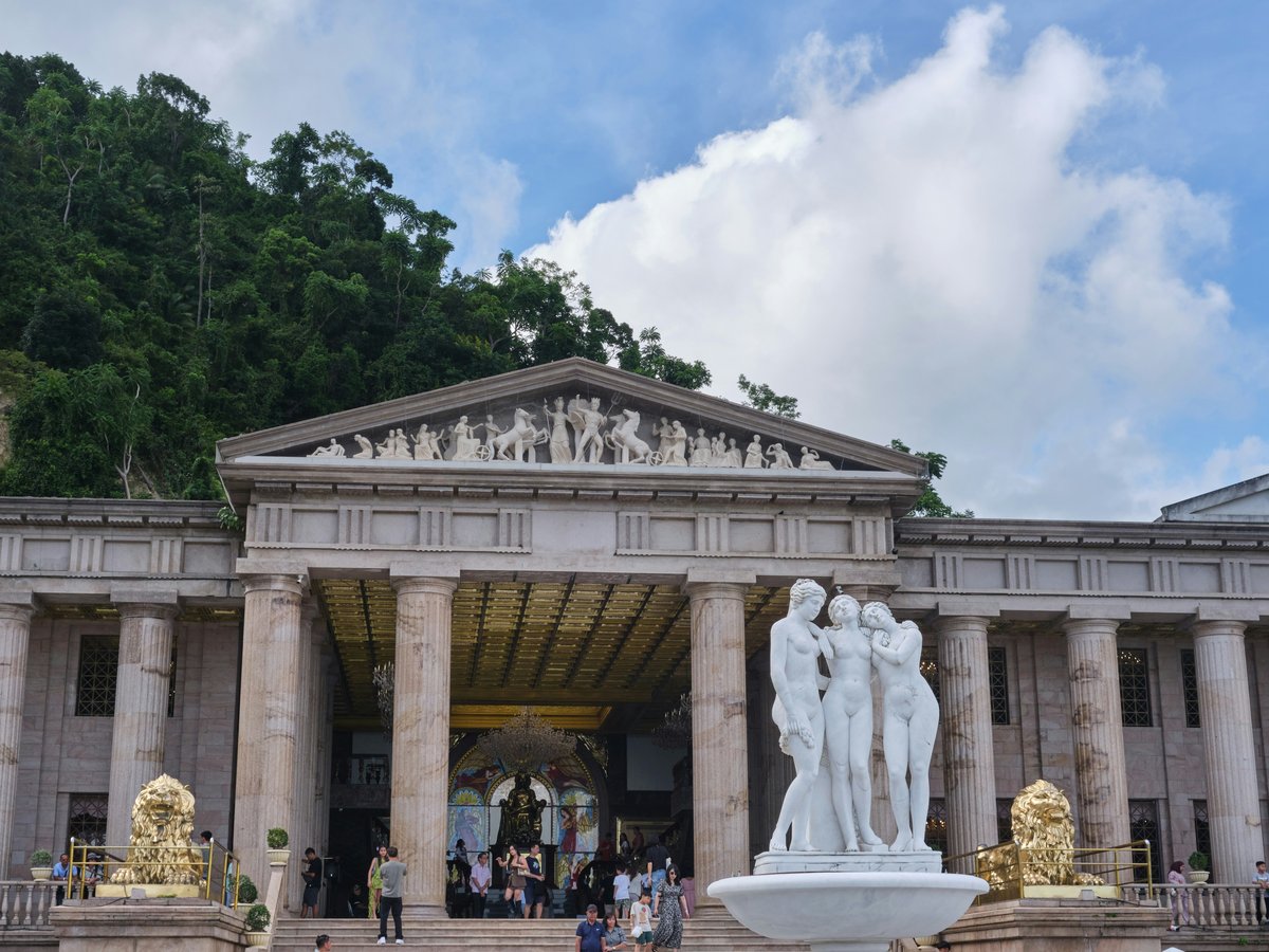 Grand building with columns and sculptures under a cloudy sky