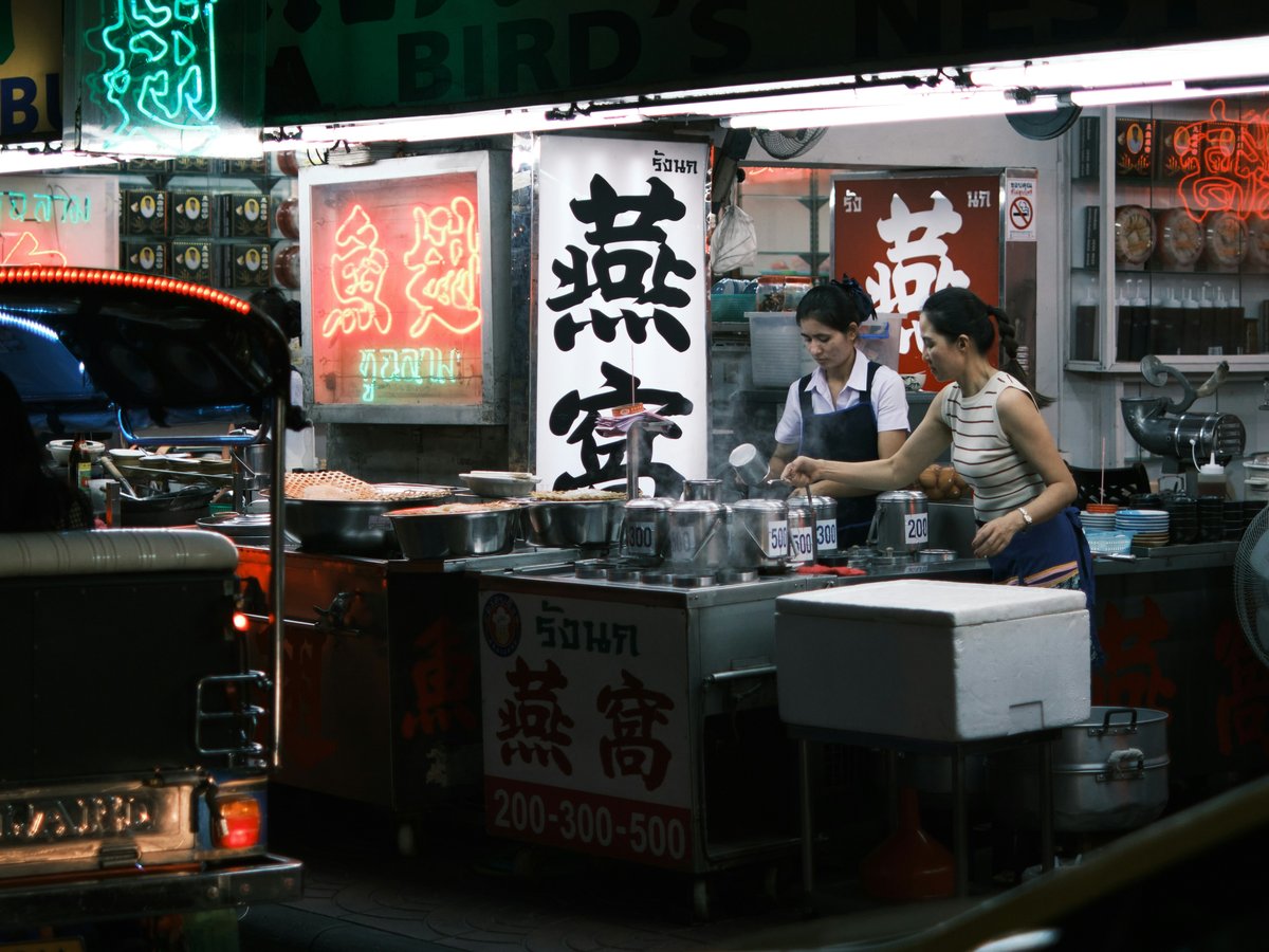a woman standing in front of a food stand at night