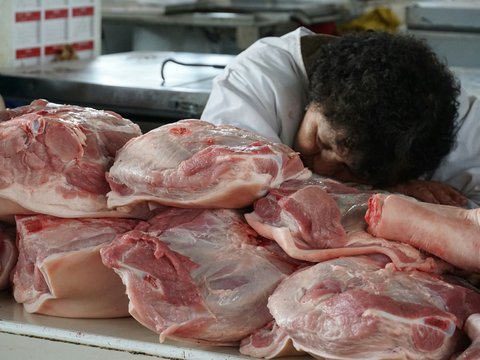 Butcher rests head on pile of raw pork cuts