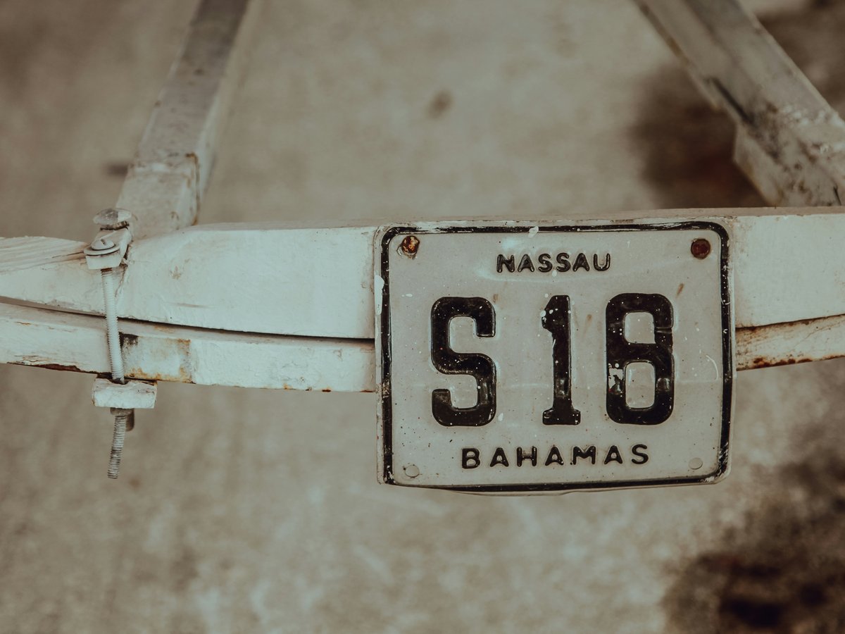 shallow focus photography of white Massau S18 Bahamas license plate mounted on white steel frame