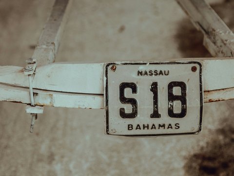 shallow focus photography of white Massau S18 Bahamas license plate mounted on white steel frame
