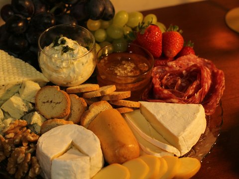 a platter of cheese, crackers, fruit and nuts