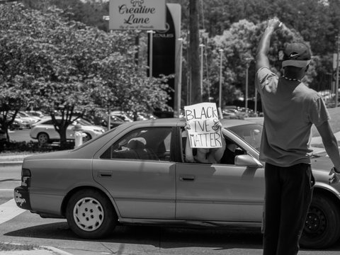 grayscale photo of man in black shirt and pants standing beside car