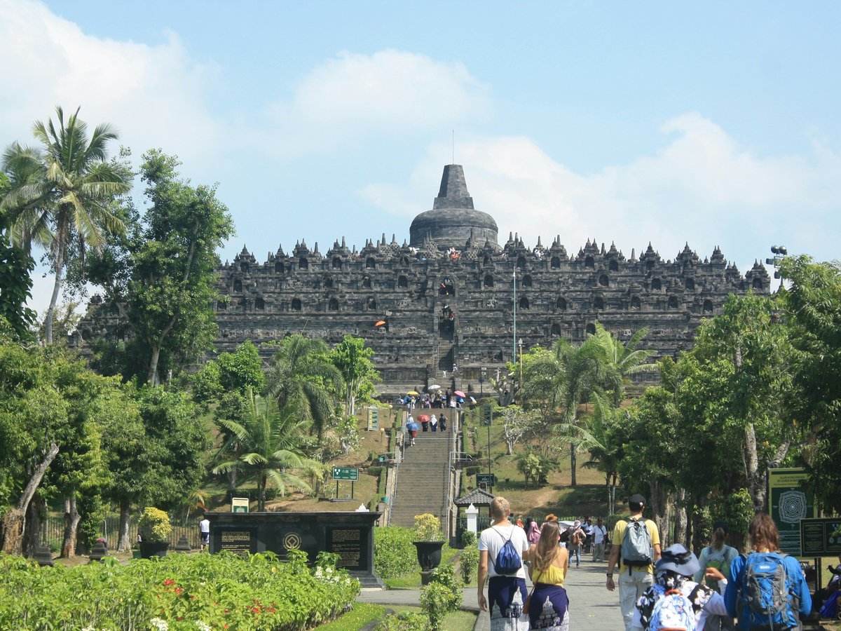 a group of people walking down a path next to a large building