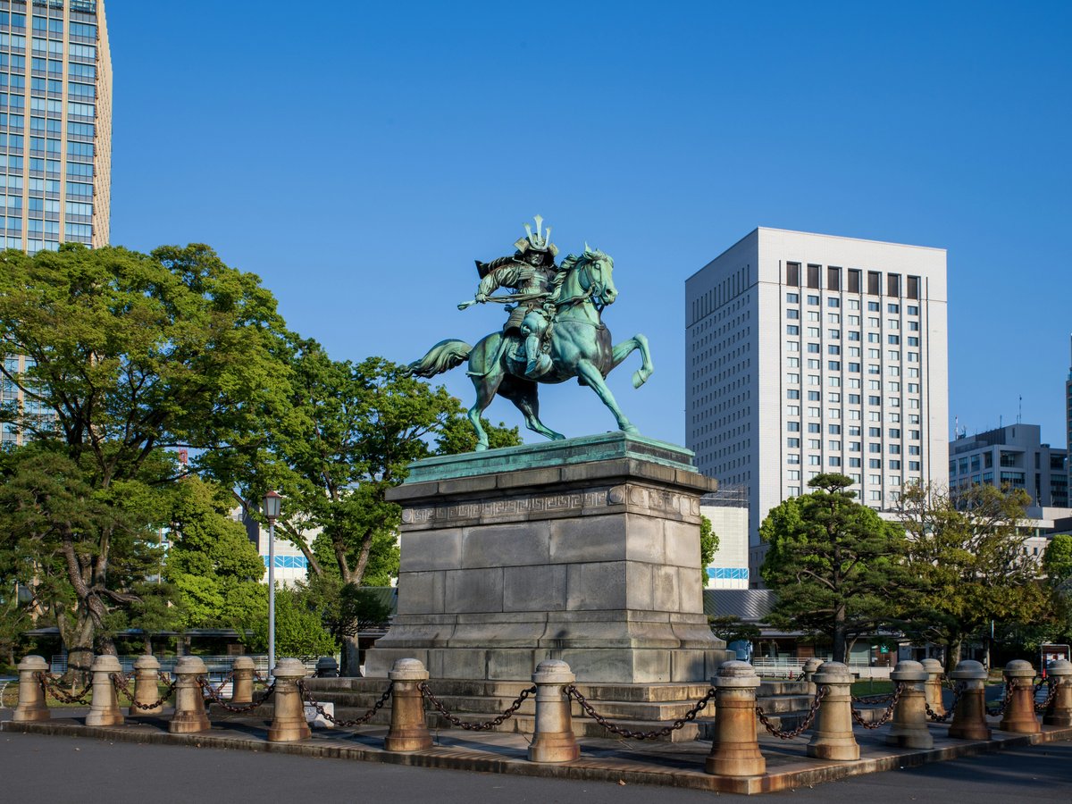 Equestrian statue in front of modern buildings and trees