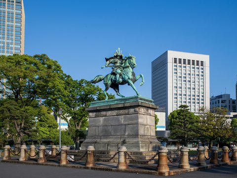 Equestrian statue in front of modern buildings and trees