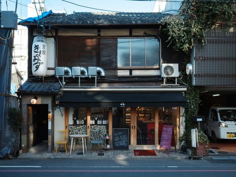Traditional japanese building with shop and parked vehicle.