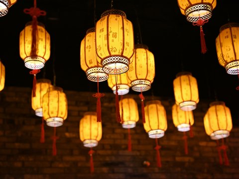 a bunch of yellow lanterns hanging from a ceiling