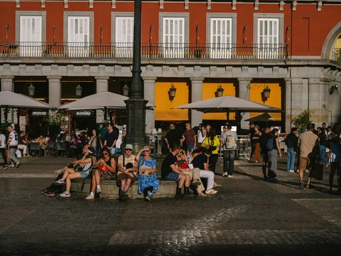 People relaxing in a plaza in front of a building.