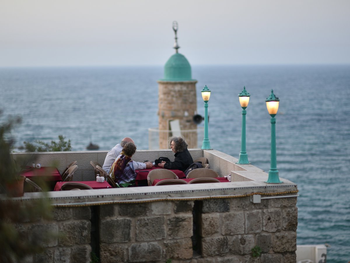people dining on roof top of building near body of water