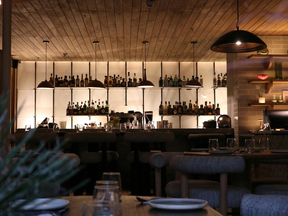 a dimly lit restaurant with bottles of wine on the wall