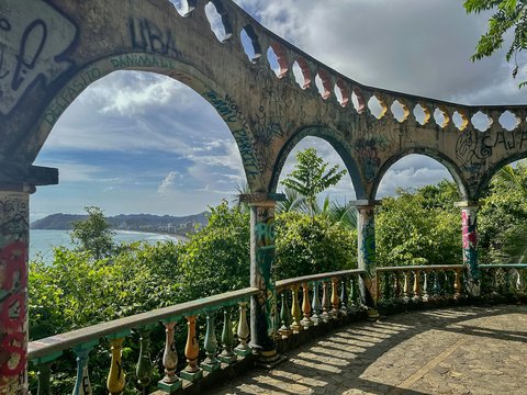 Arched ruins overlook a lush green landscape and ocean