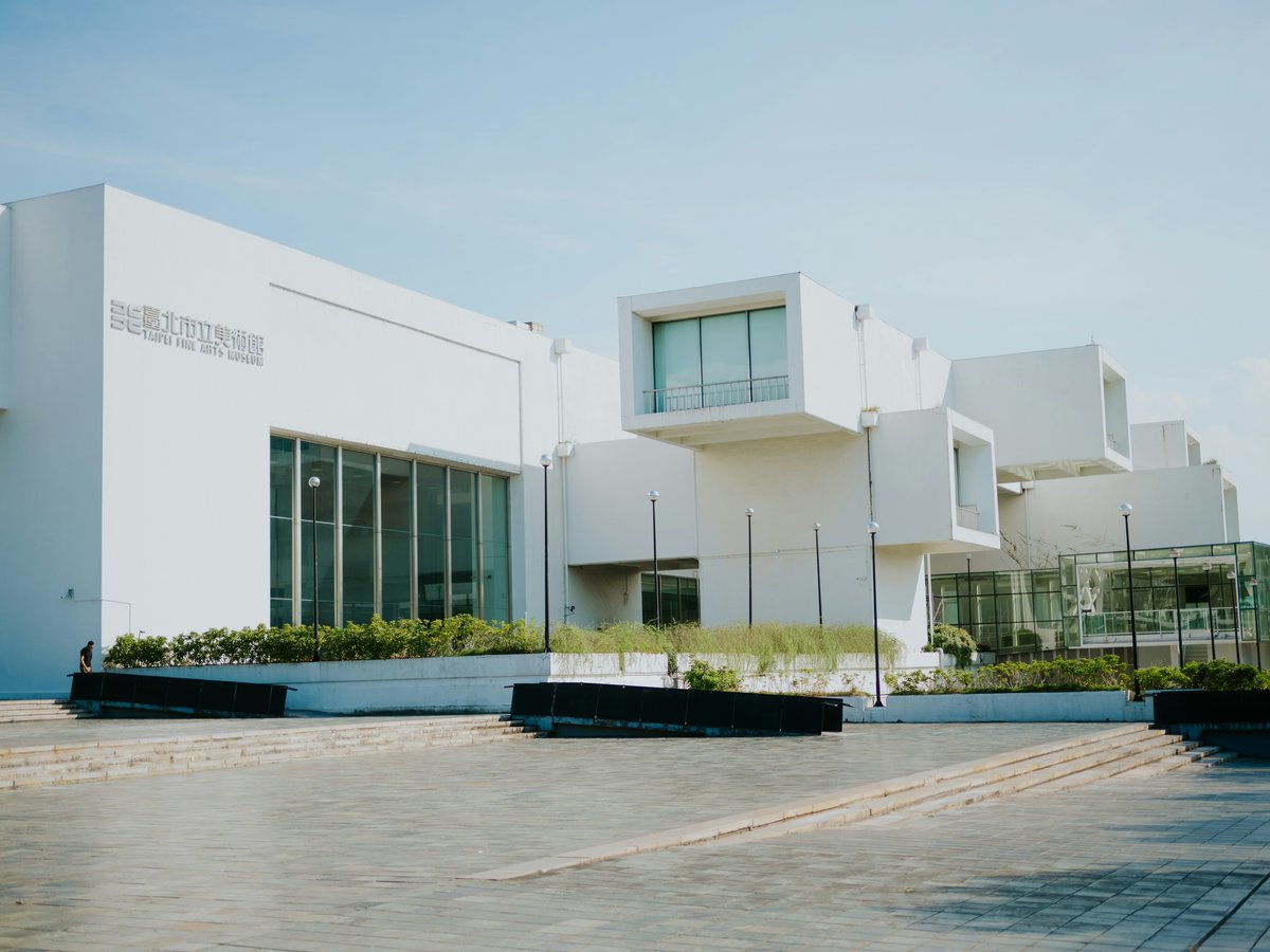Modern white building with geometric architecture under a clear sky.