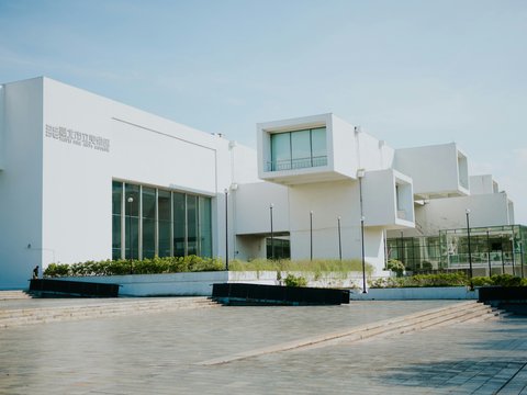 Modern white building with geometric architecture under a clear sky.