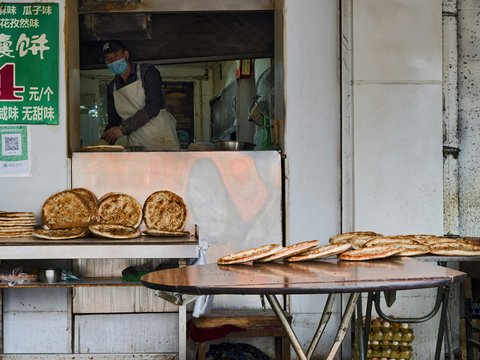 Baker preparing flatbreads at an outdoor stall