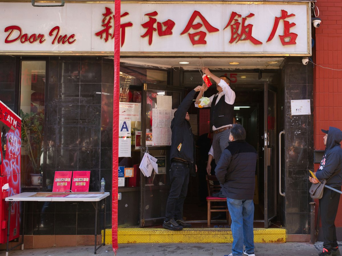 Men hang sign above chinese restaurant entrance