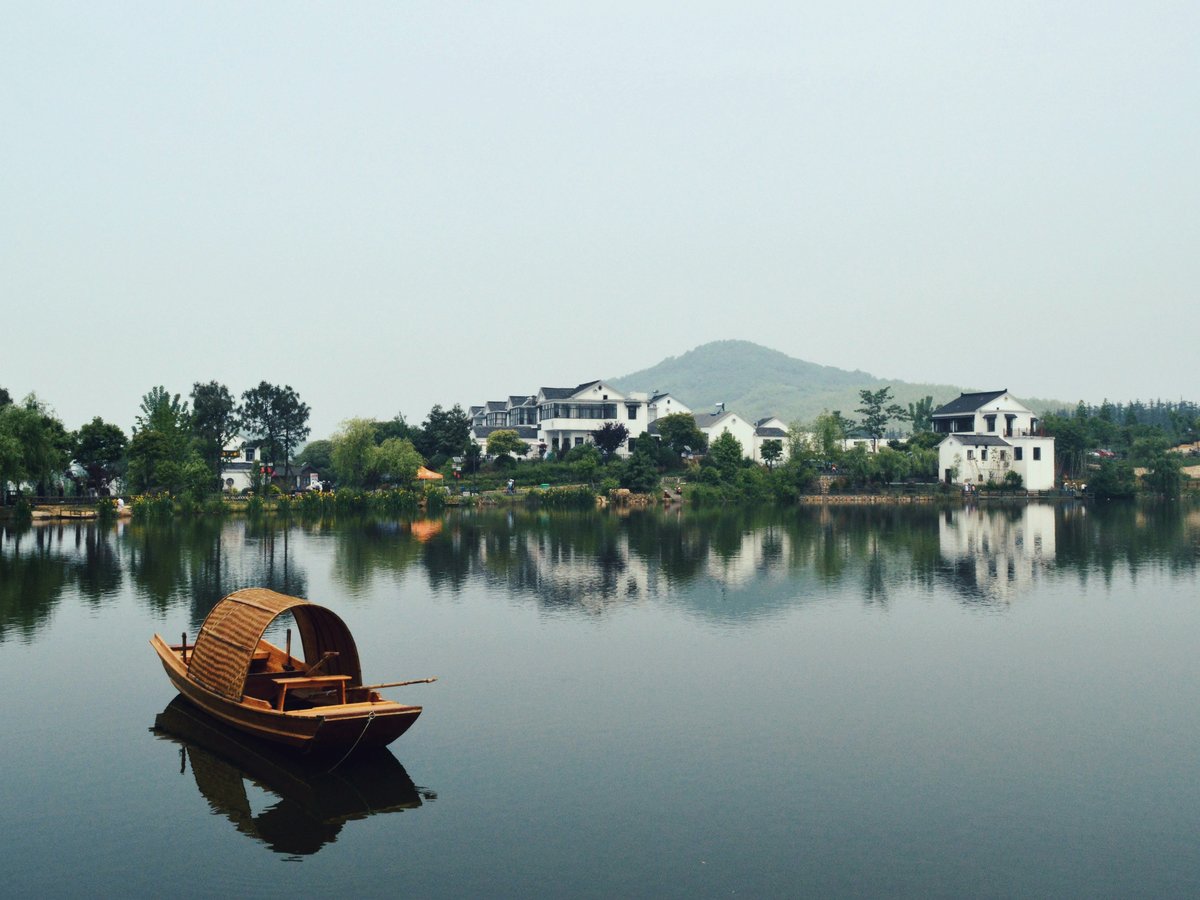 brown wooden boat on body of water overlooking houses by the shore at daytime
