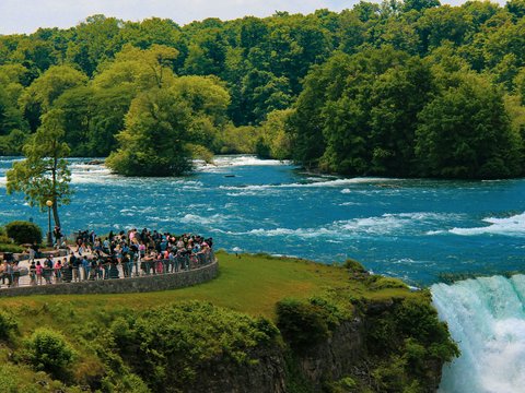 A large group of people standing on the side of a river