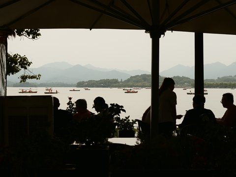 Silhouetted people enjoy a scenic lake view with mountains.