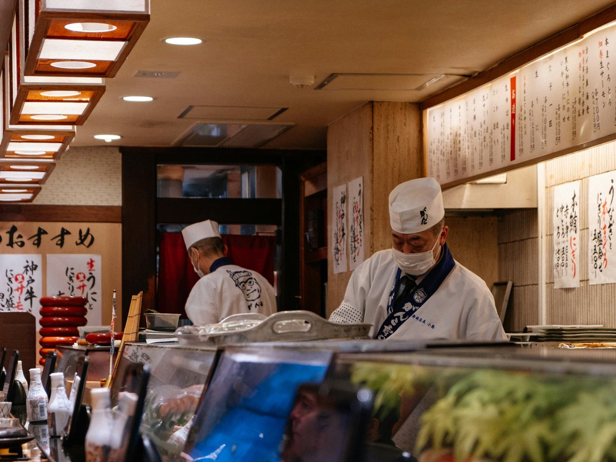Sushi chefs preparing food in a japanese restaurant.