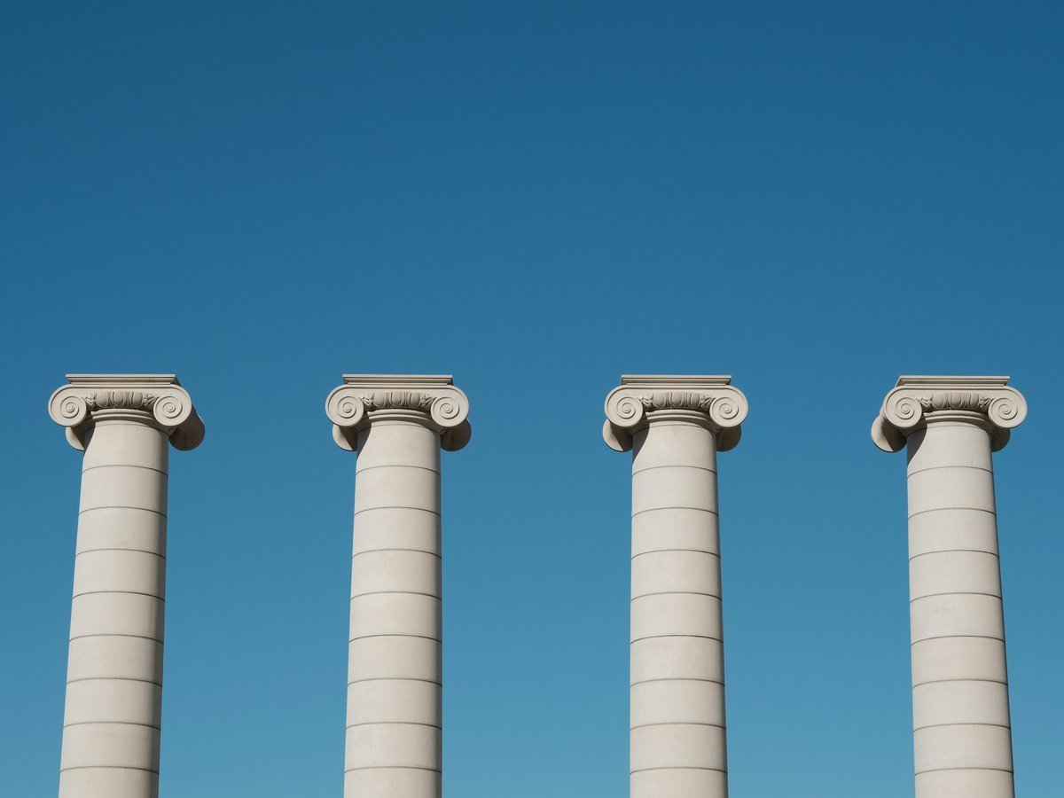 a row of white pillars against a blue sky