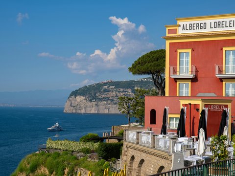 A red and yellow building sitting on top of a cliff next to the ocean