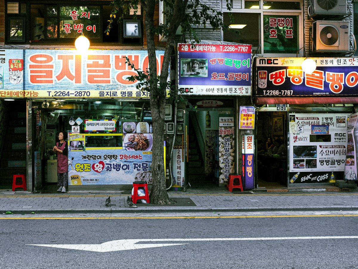 A street scene with a store front and a car parked on the side of the