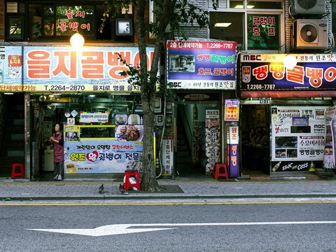 A street scene with a store front and a car parked on the side of the