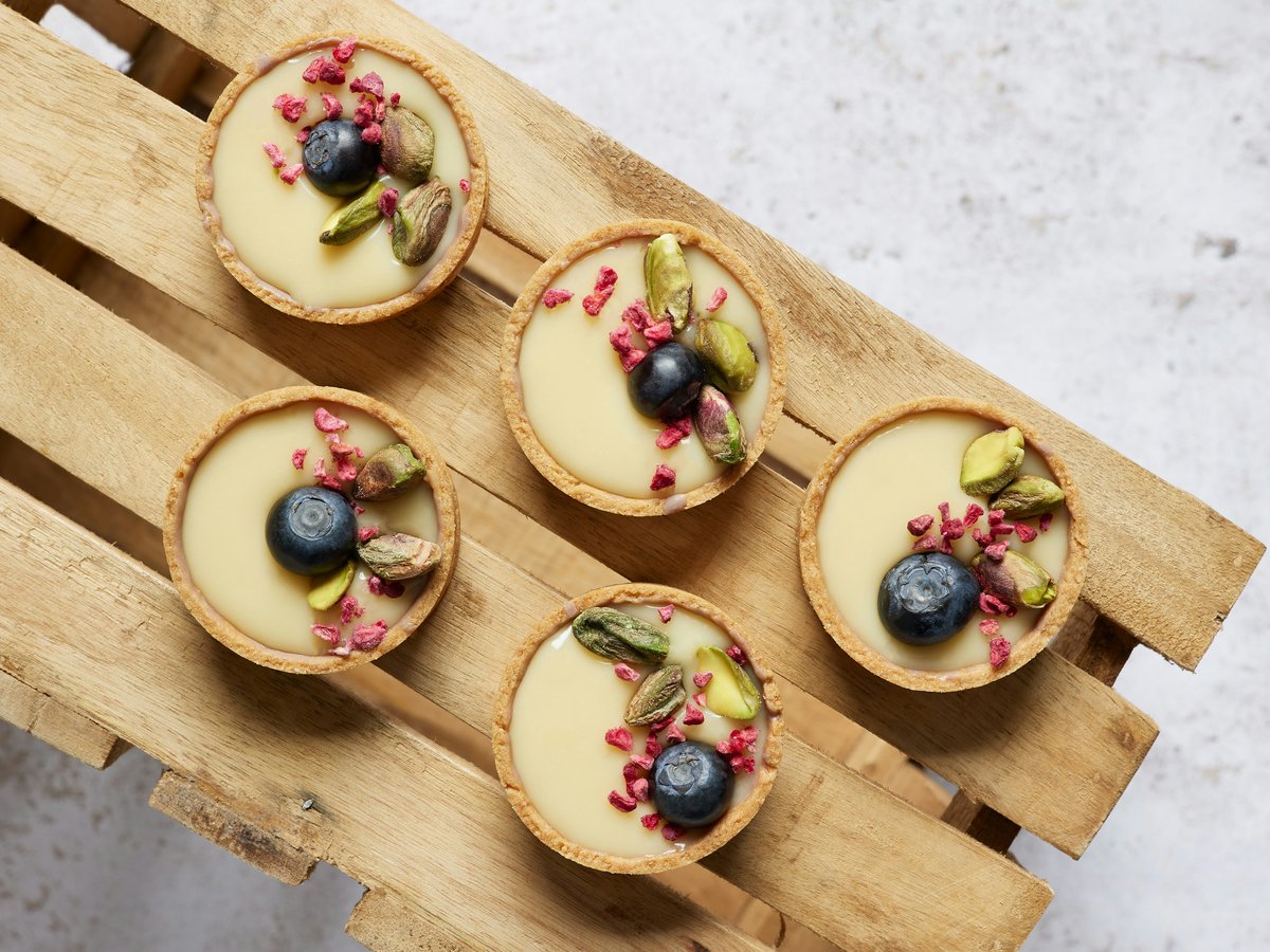 four desserts are arranged on a wooden tray