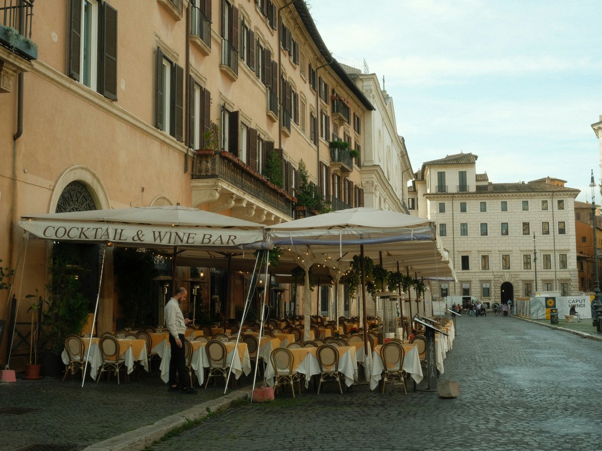A restaurant with tables and buildings in rome.
