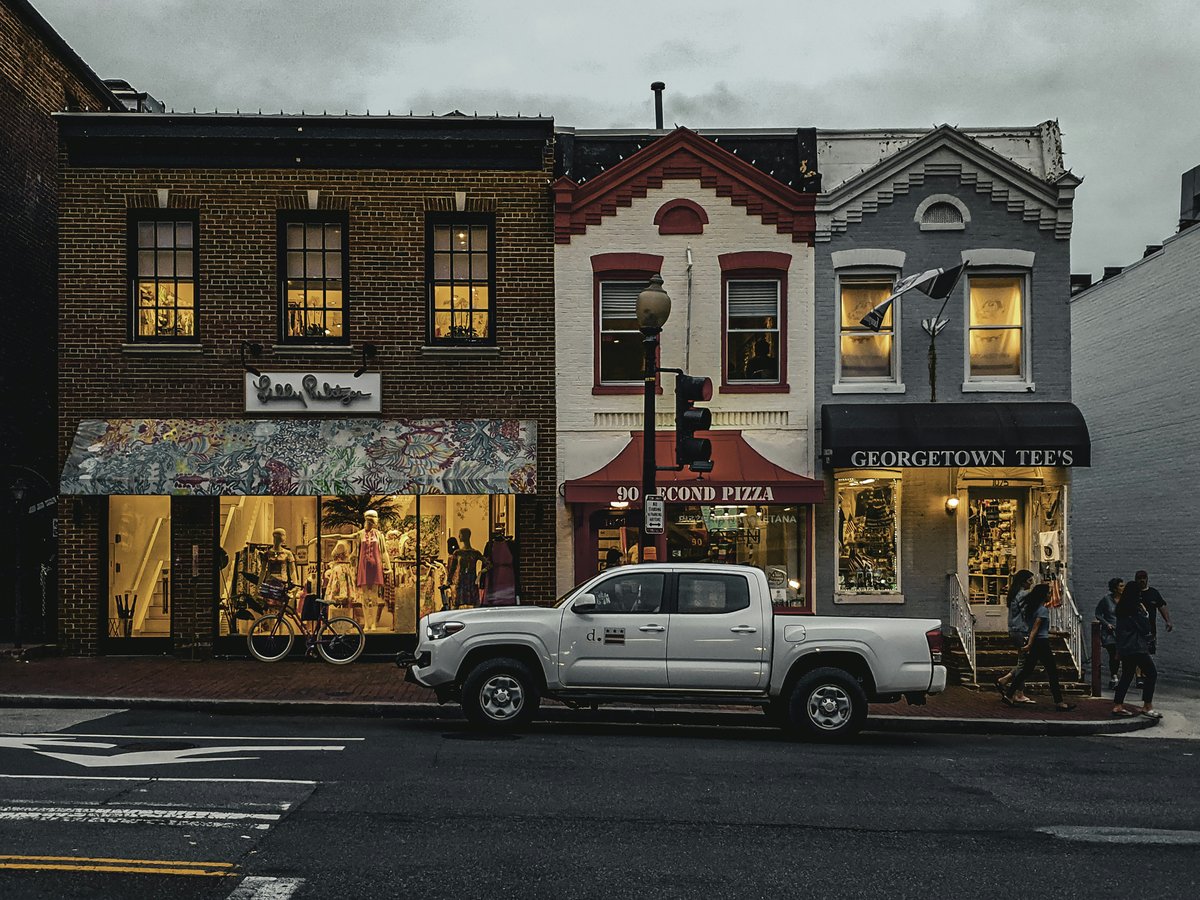 Shops and a truck line a colorful street