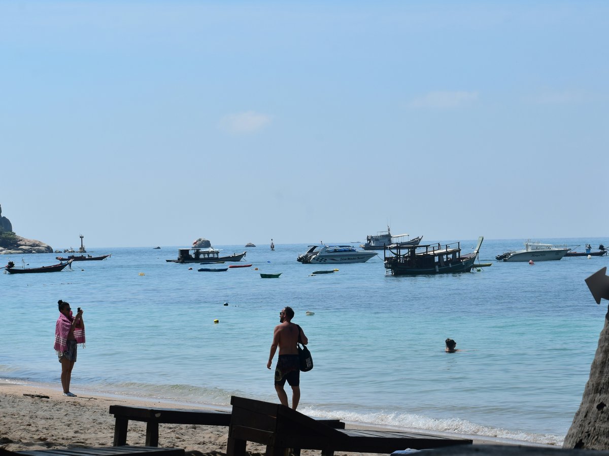 People on a beach with boats in the ocean